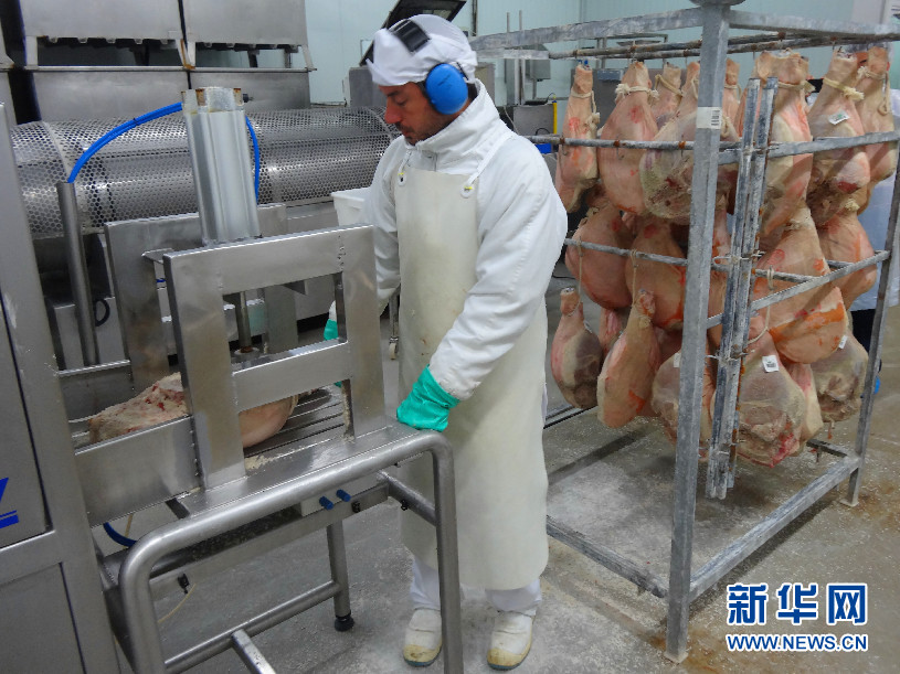 工人将猪腿取出，挂在身后的架子上。